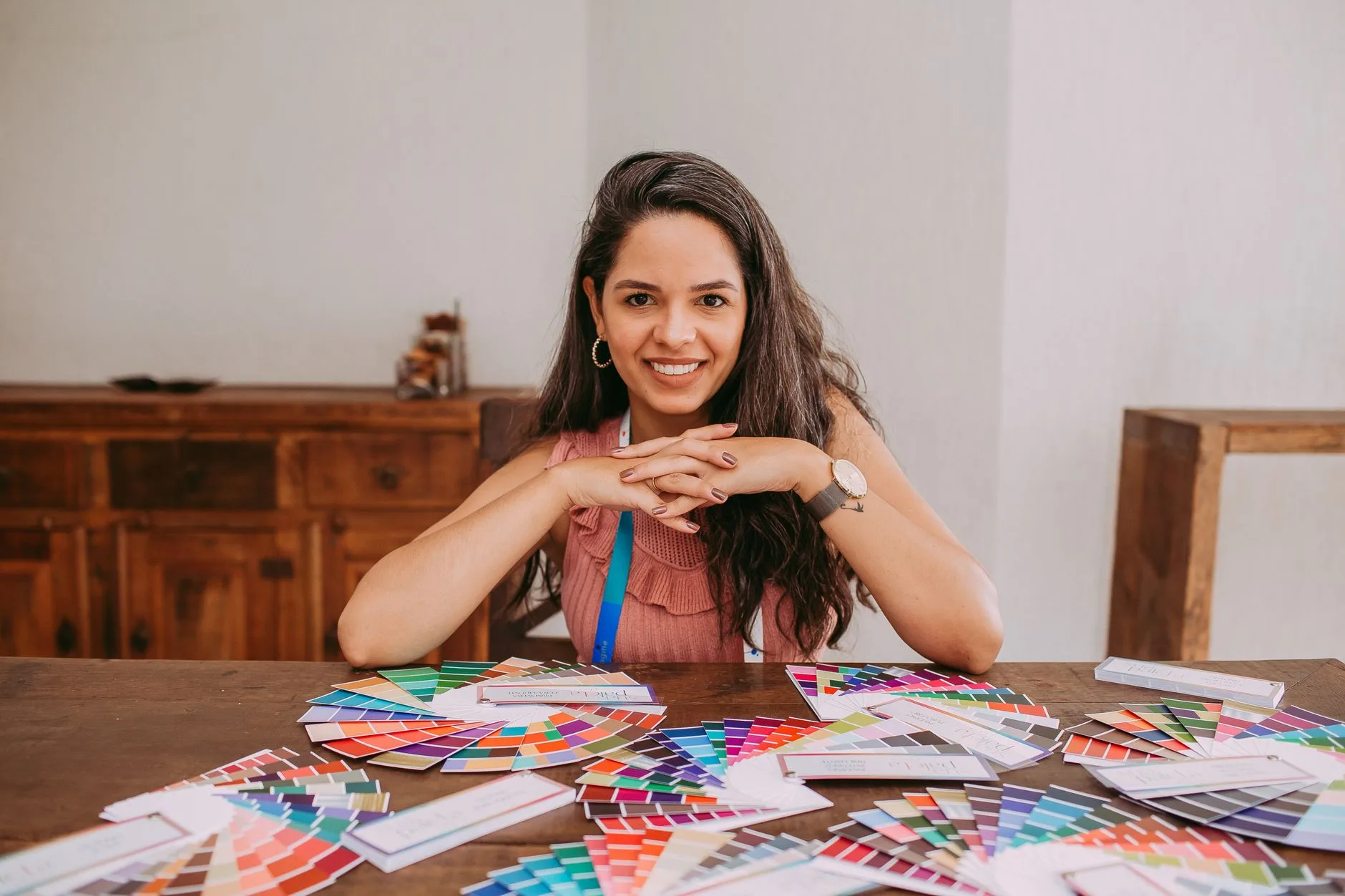 A designer smiling at a desk covered in printed color palette swatches