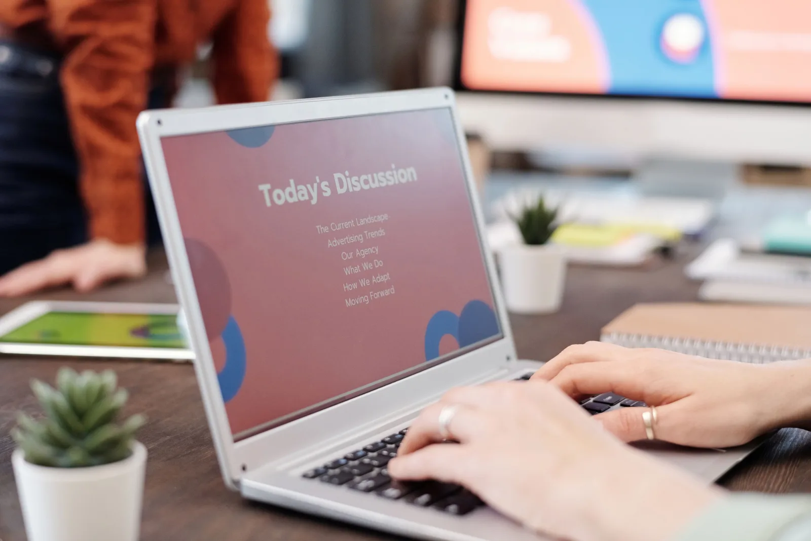 Hands typing on a laptop that shows an agenda slide titled Today's Discussion