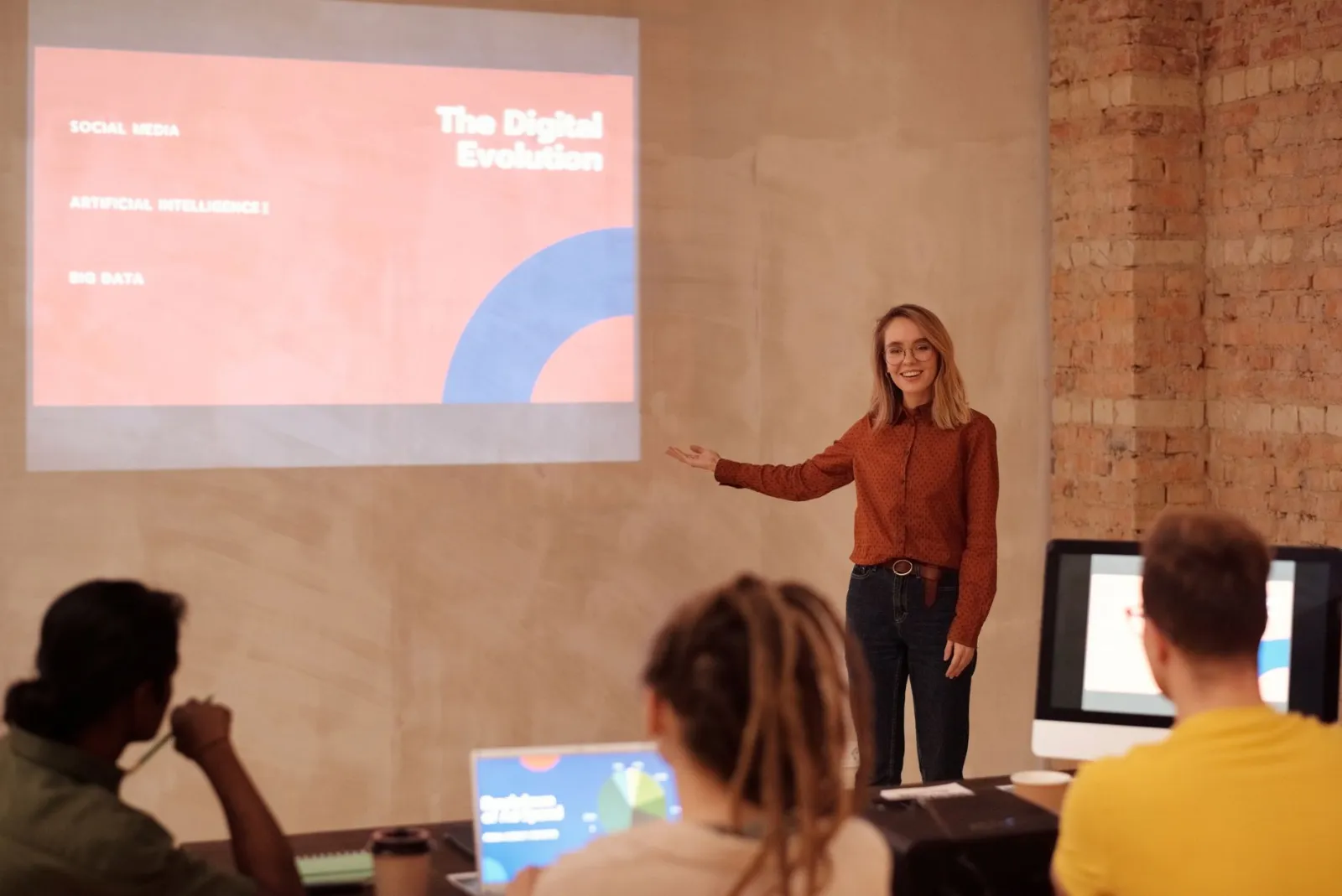 Presenter gesturing toward a projected slide titled The Digital Evolution during a talk