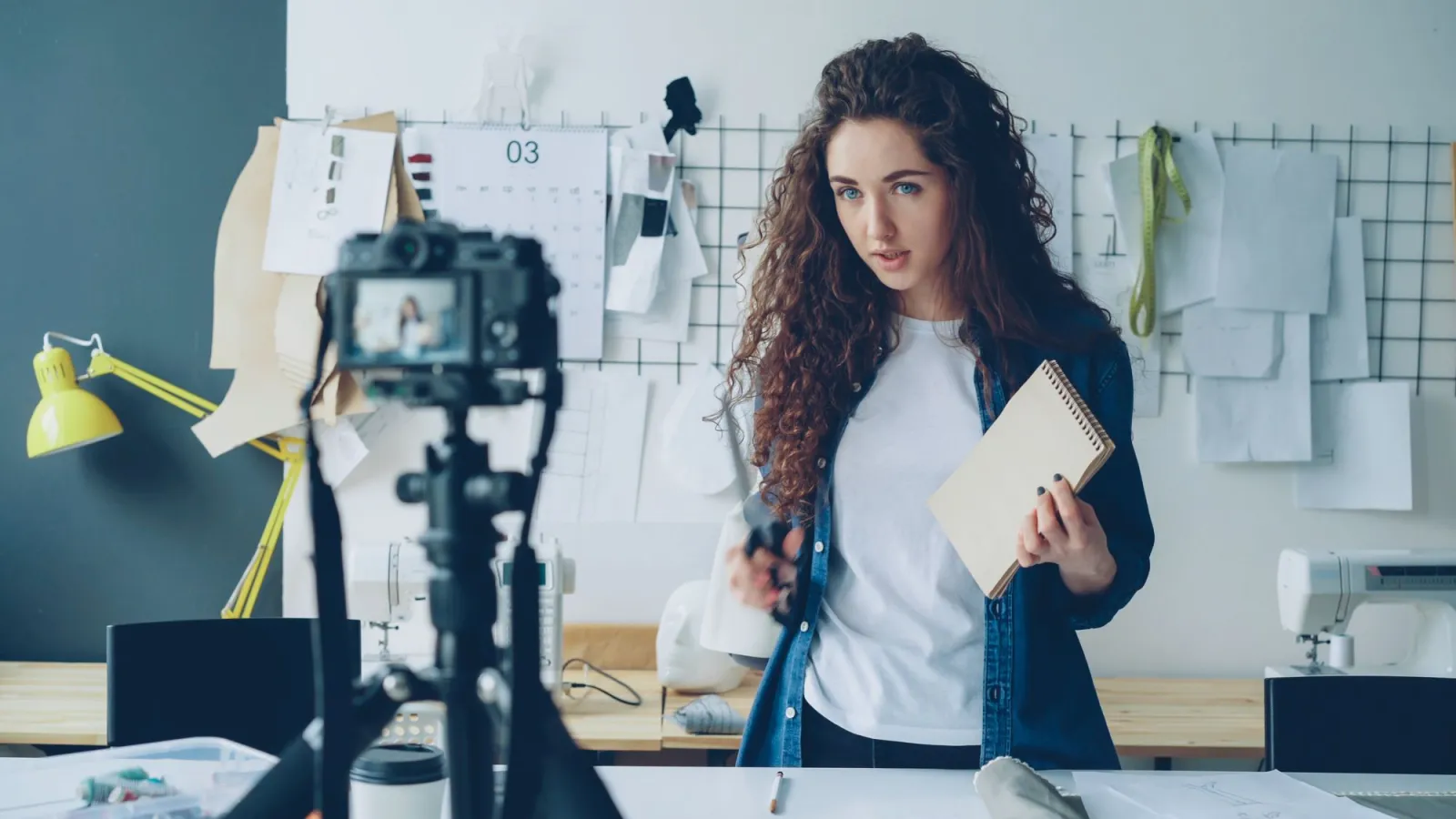 A content creator recording a video at a desk with camera and lighting gear