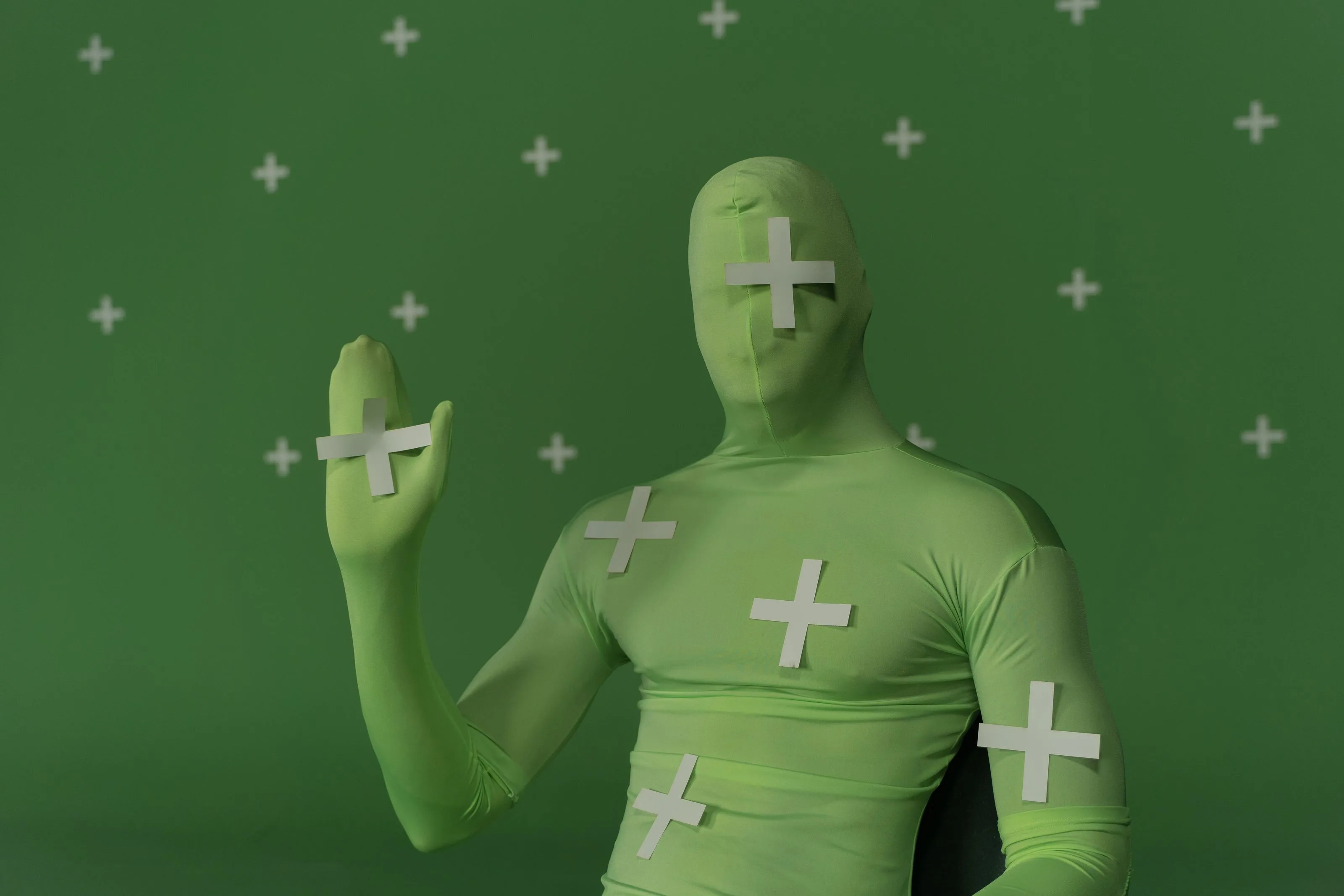 Performer in a green chroma-key suit with white tracking crosses for visual effects