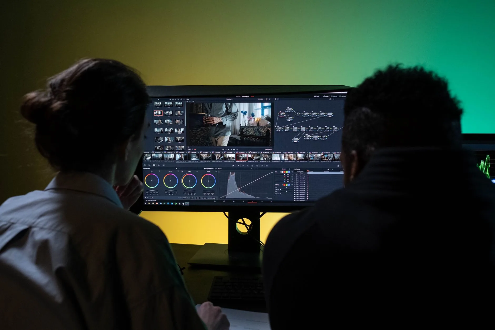 Two professionals video editing with dual monitors in a modern setup