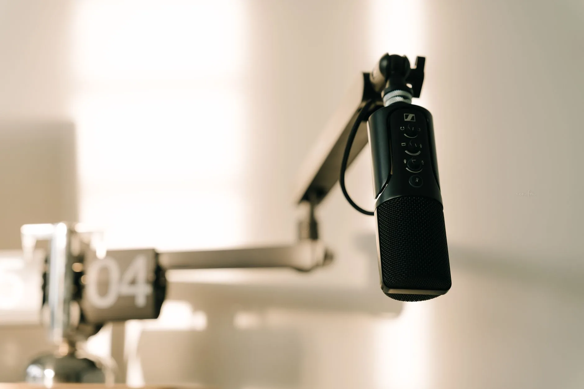 A sleek professional microphone on a boom arm in a minimalist studio