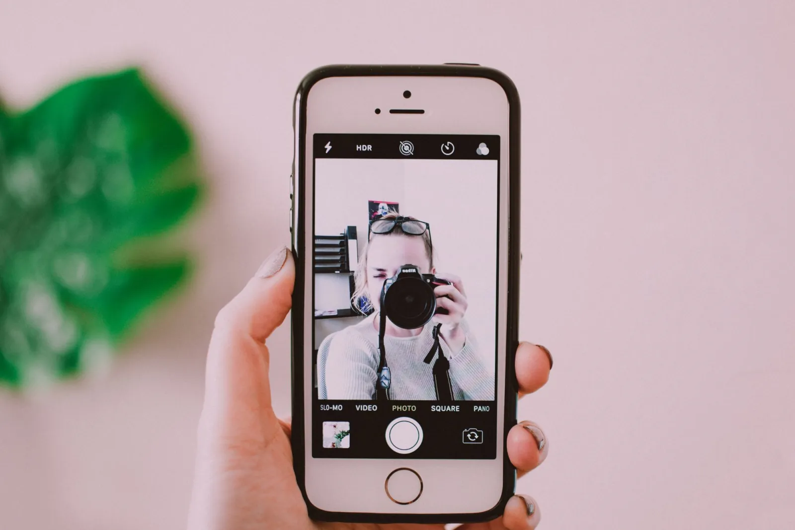 A person taking a selfie with a camera through a smartphone, demonstrating phone photography portrait mode