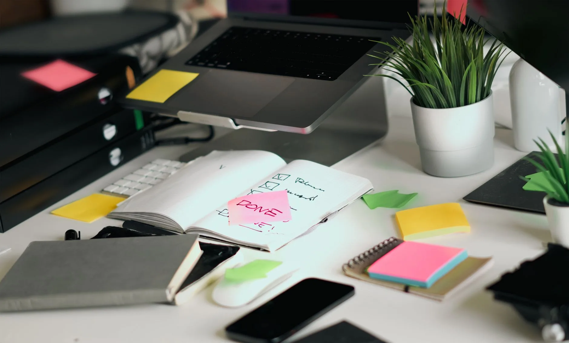 Open notebook with a handwritten checklist beside a laptop on a tidy desk