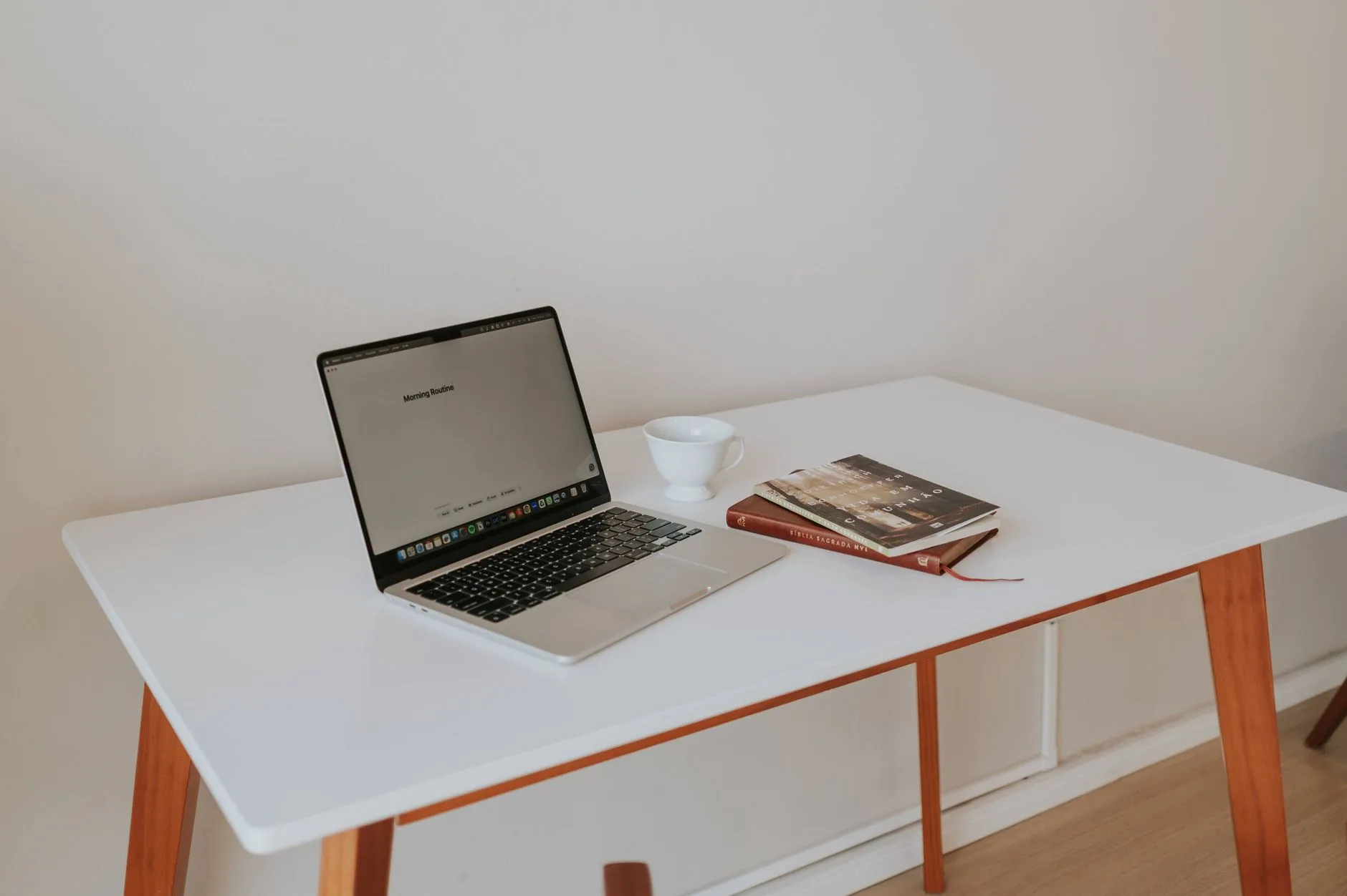 Minimal, calm workspace with a laptop and coffee on a clean white desk