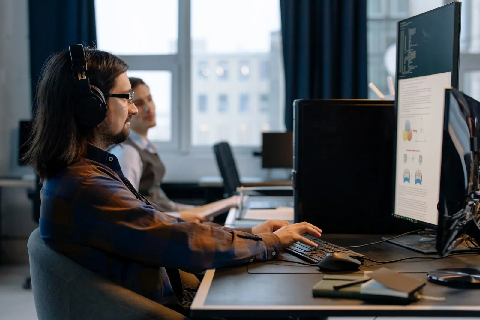 Two programmers focused on coding side by side in a modern office