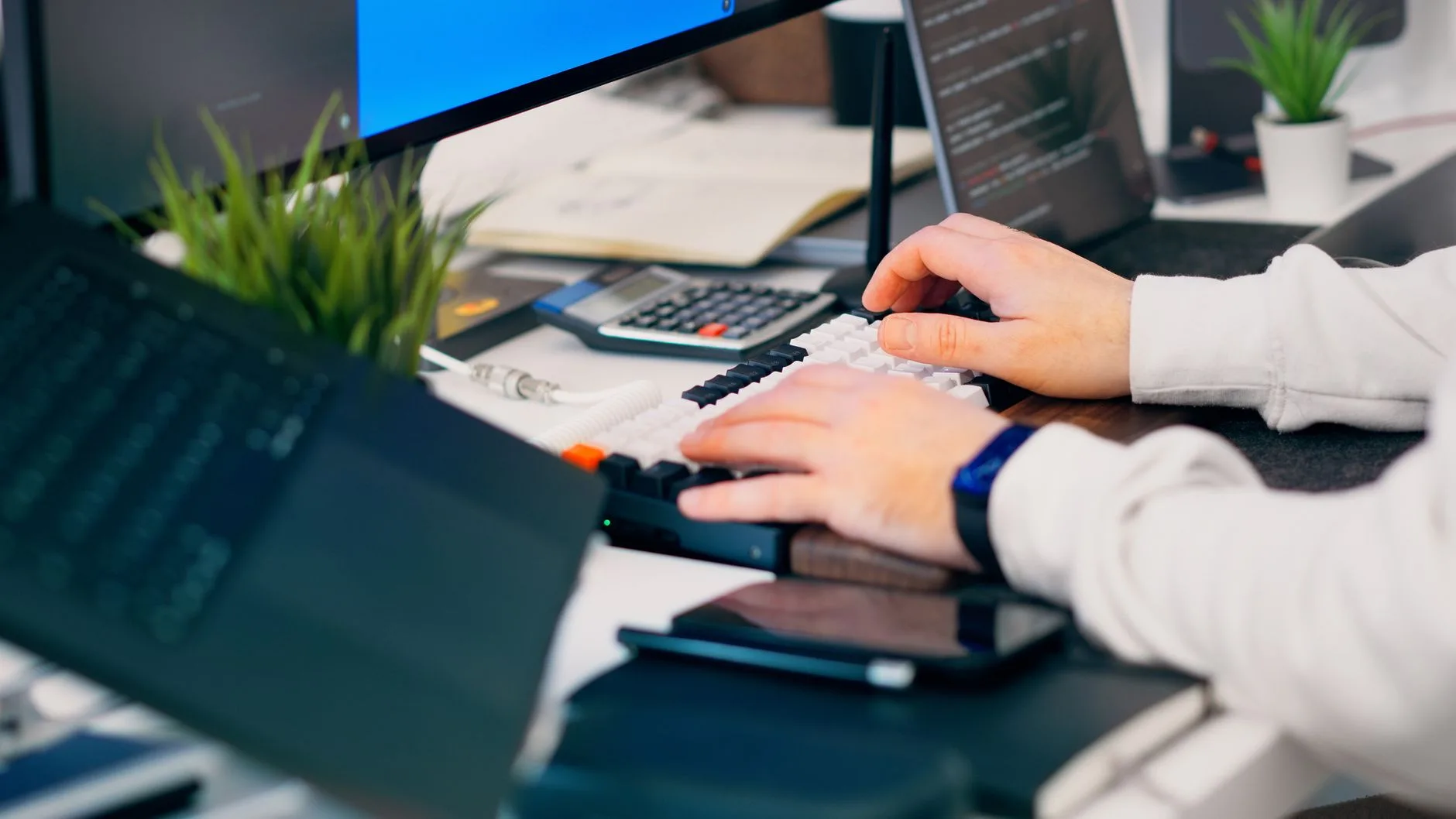 Hands typing on a mechanical keyboard at a tidy desk while running a terminal refactor