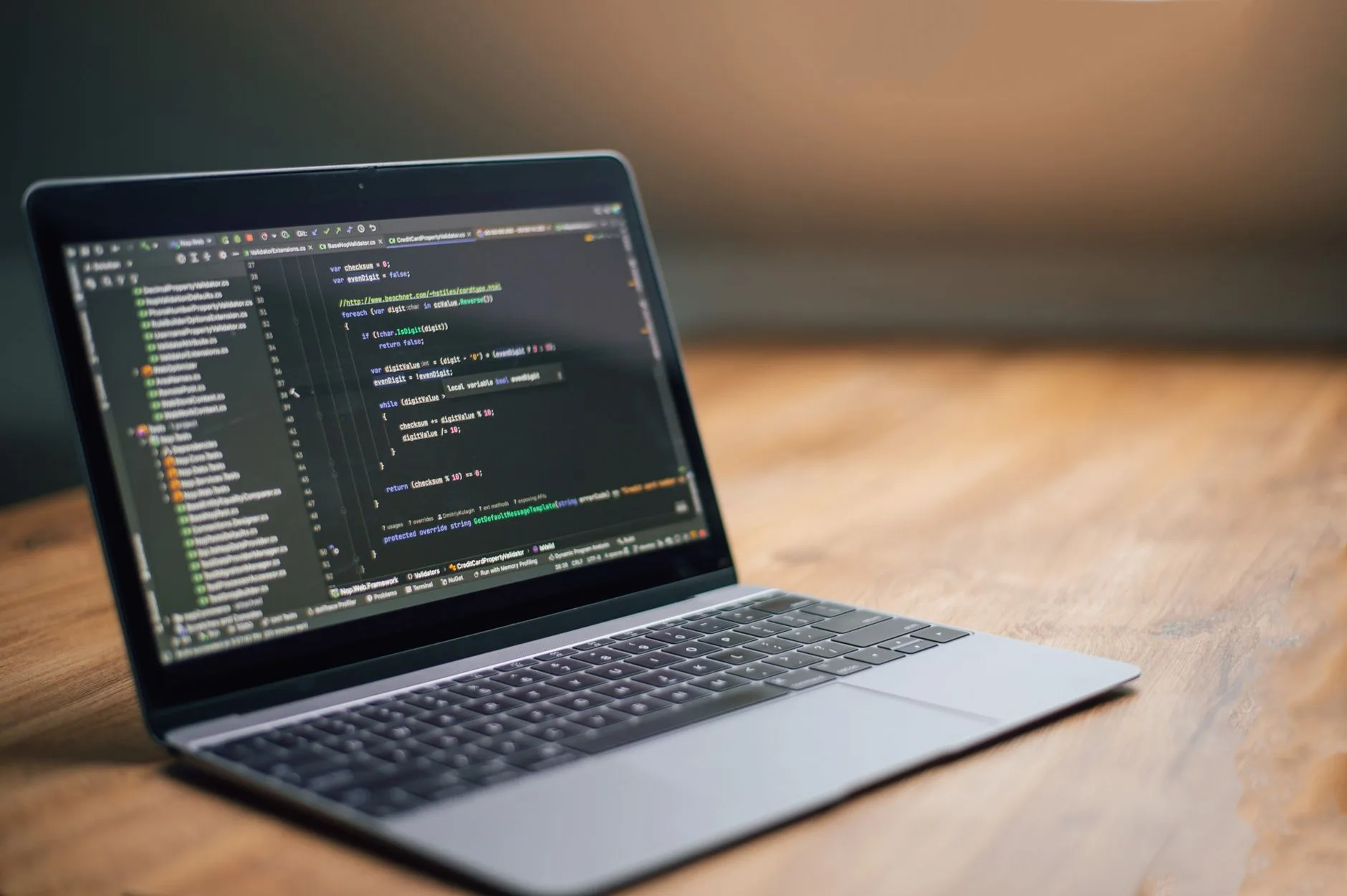 Laptop on a wooden desk showing source code in an editor, a typical solo coding setup