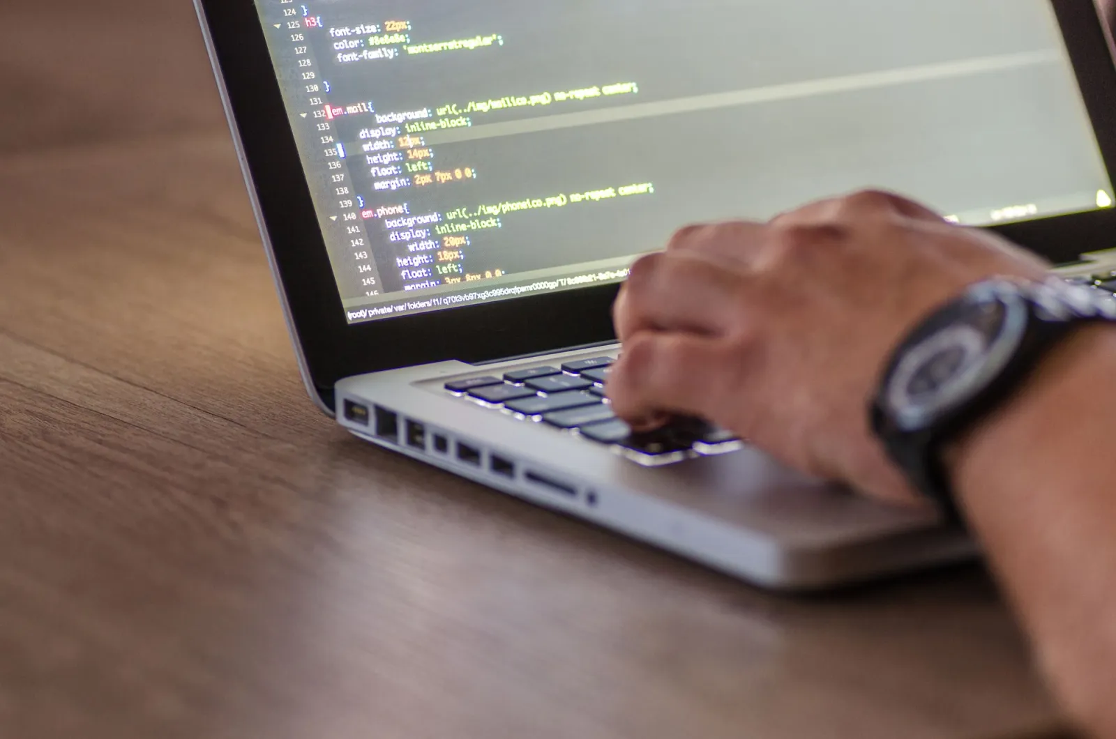 Close-up of a developer coding on a laptop while reviewing installed packages