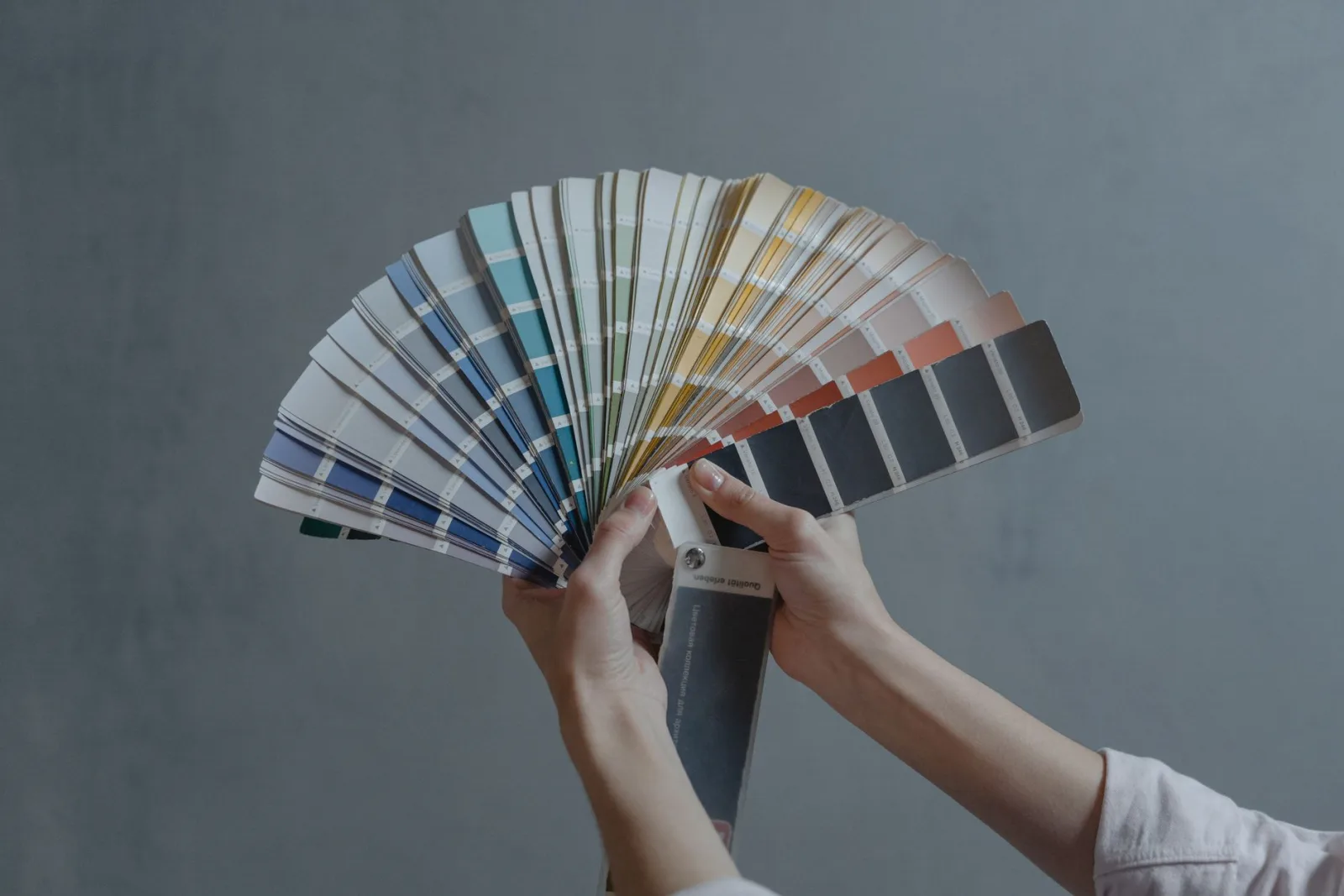 Hands holding a colorful fan of fabric swatches, illustrating how extraction groups similar hues