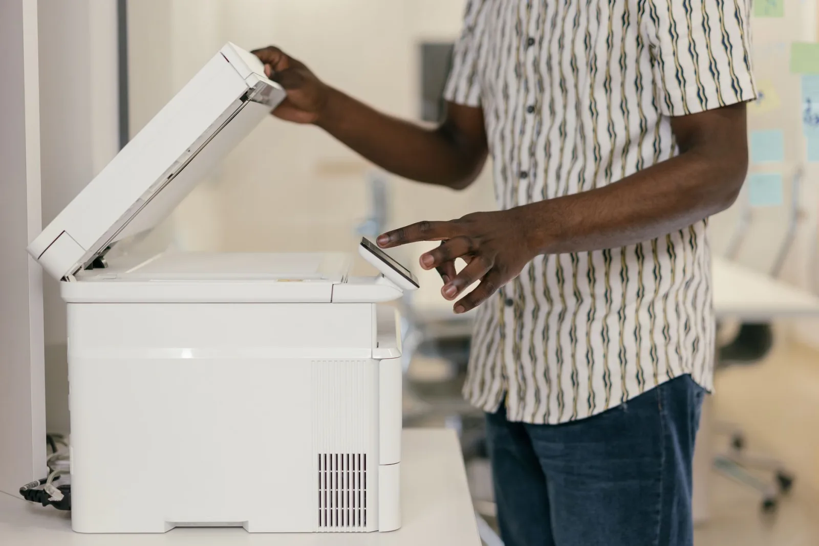 Person using an office scanner and copier to turn paper pages into a digital file