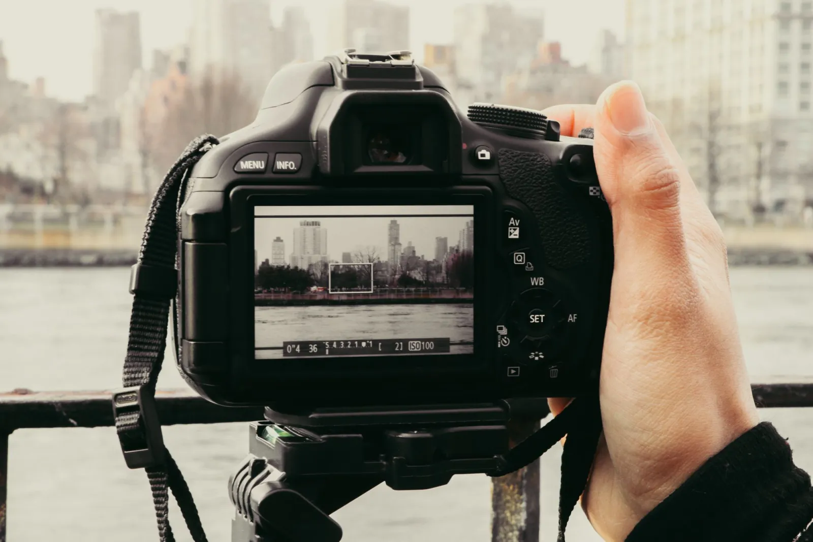 A photographer framing a city skyline through a camera viewfinder to apply the rule of thirds