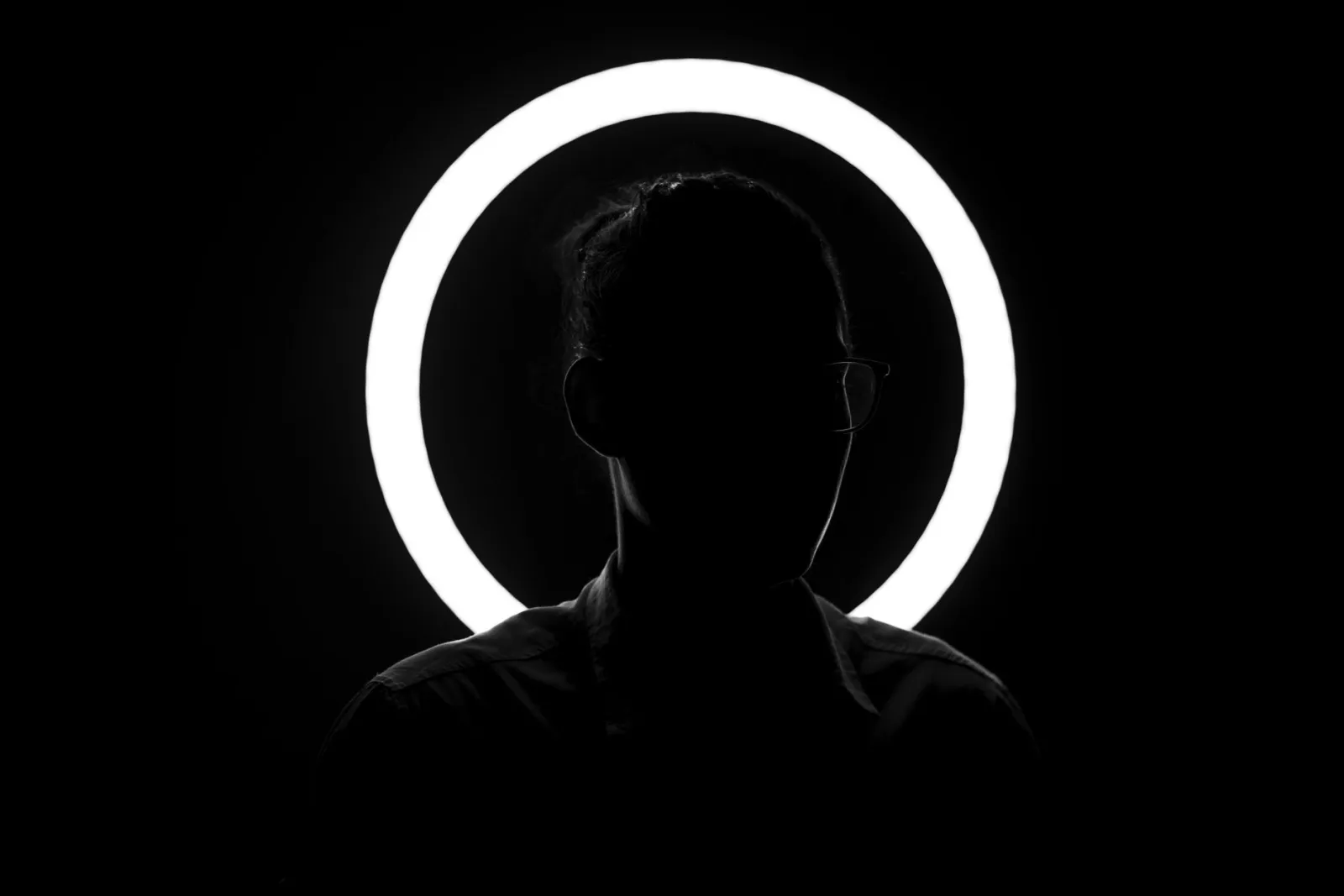 Mysterious black and white silhouette with a glowing ring light effect.