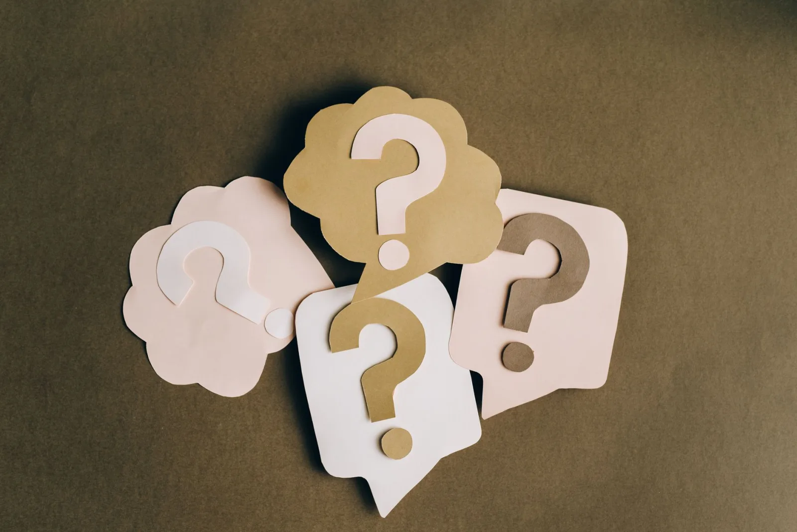 Four paper question marks cut out, representing the questions this FAQ answers