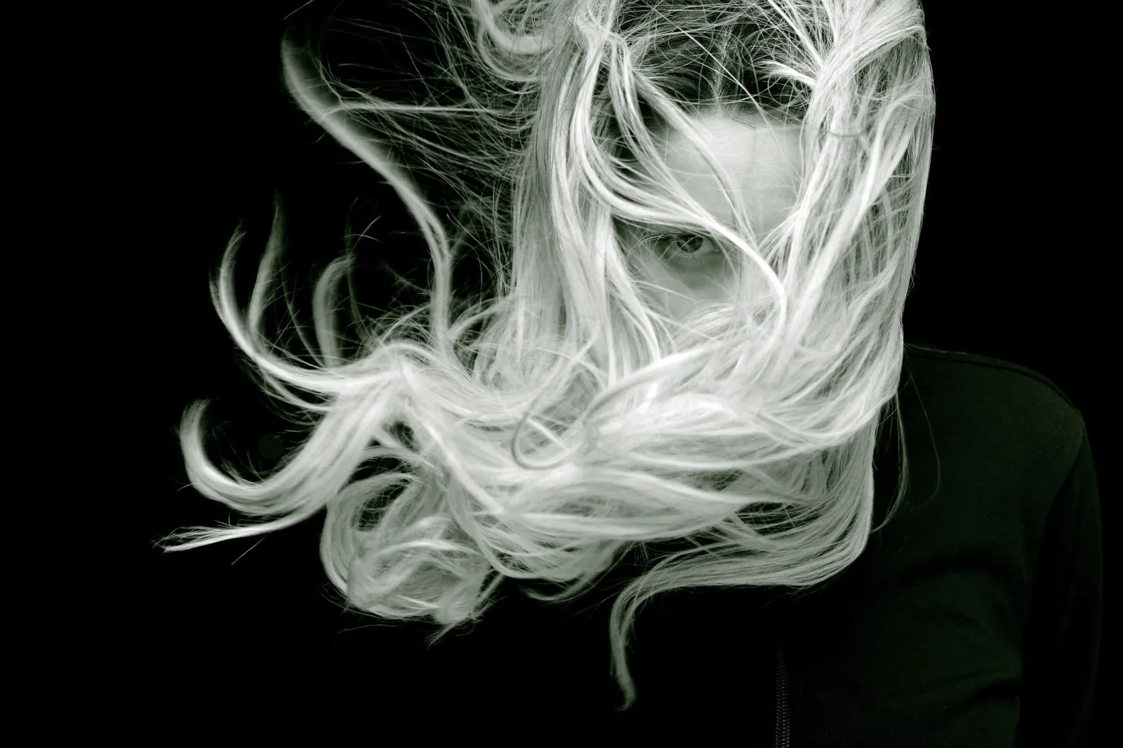 Black and white portrait of flowing hair in motion, showing the fine strand detail alpha matting must resolve pixel by pixel