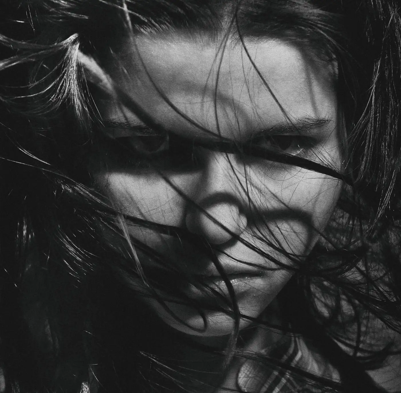 Grayscale portrait of a woman with wind-blown hair, the kind of flyaway strands that trip up AI background removal