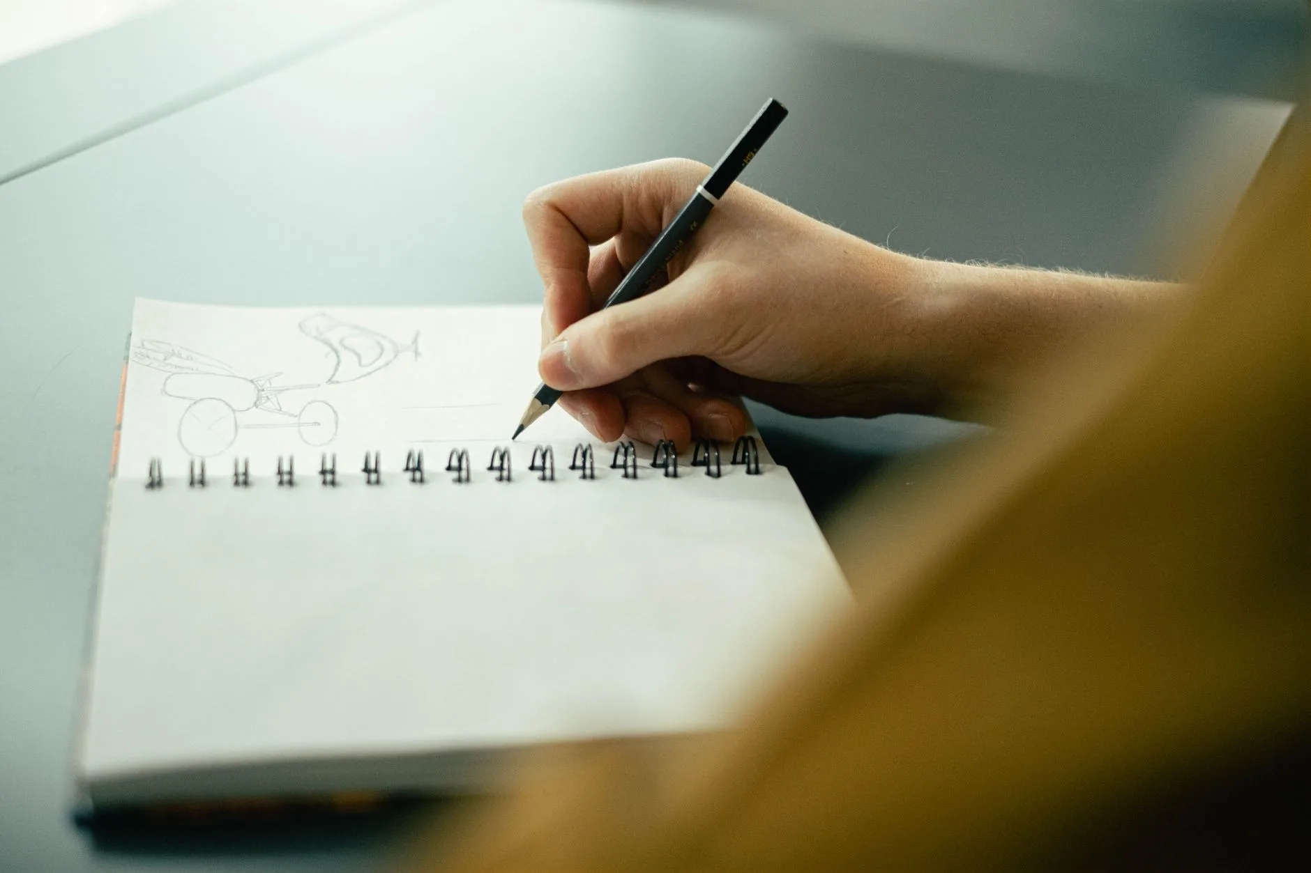 Hand sketching in a notebook with a pencil, focusing on creativity and planning