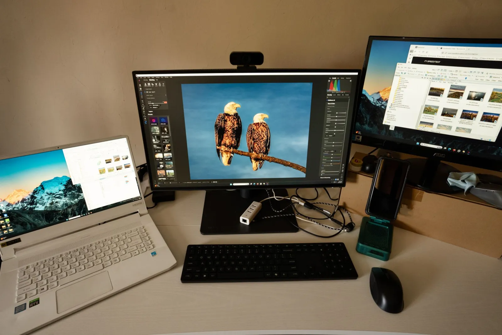 Photographer workspace with dual monitors, a laptop, and image editing software open