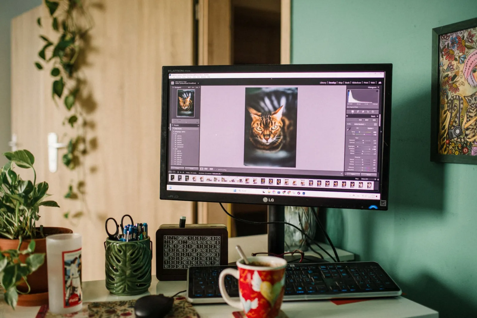 A cozy home office desk with a monitor displaying photo editing software
