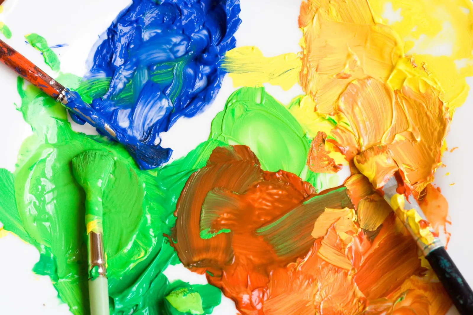 A close-up of a colorful paint palette with brushes, where screen lightens by adding light values