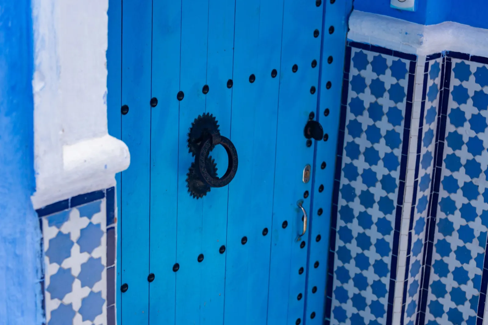 Vibrant blue ornate wooden door as a single bold color subject against muted surrounding tones
