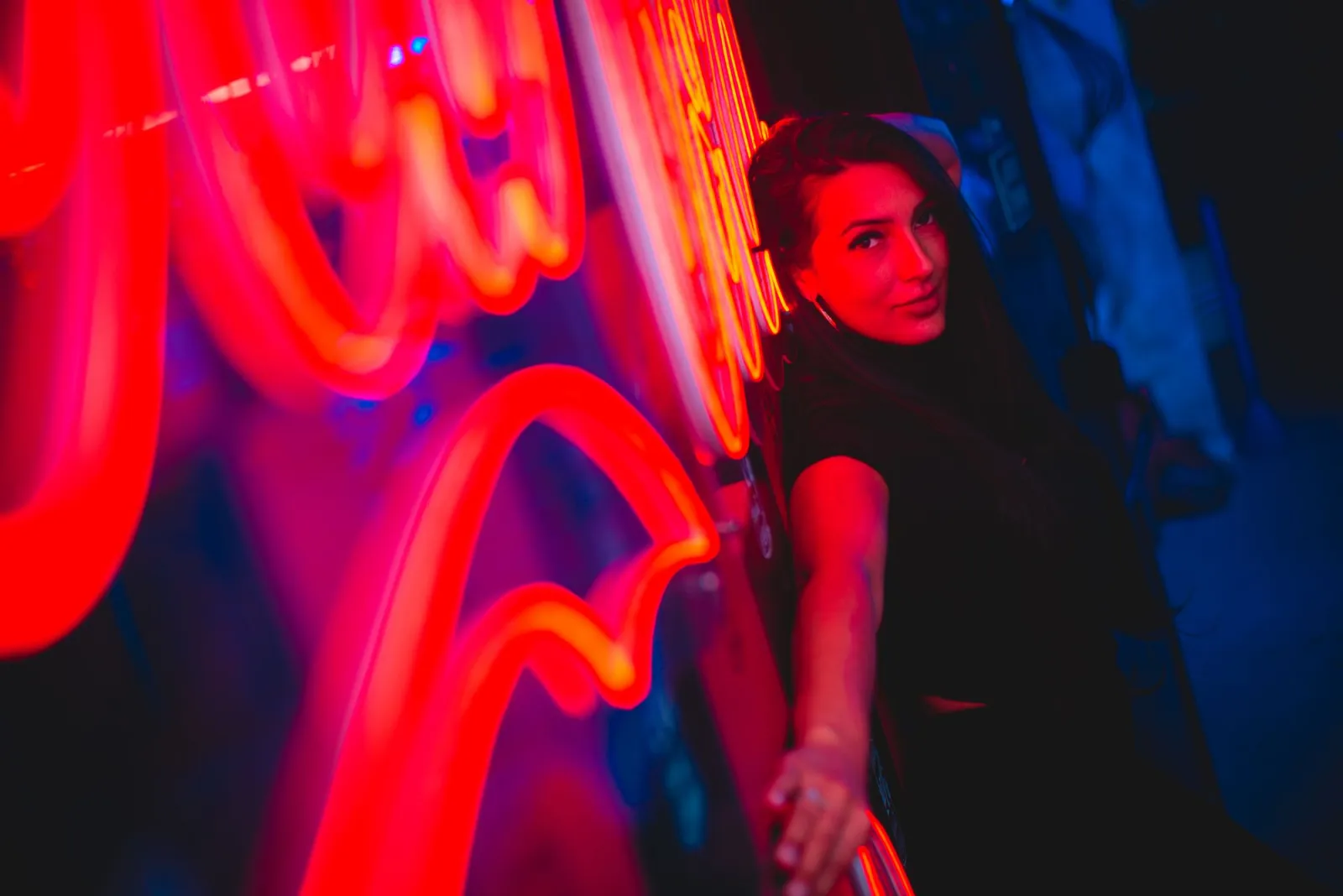 Woman leaning near a neon sign, showing where glow should touch hair and clothing without washing out the face