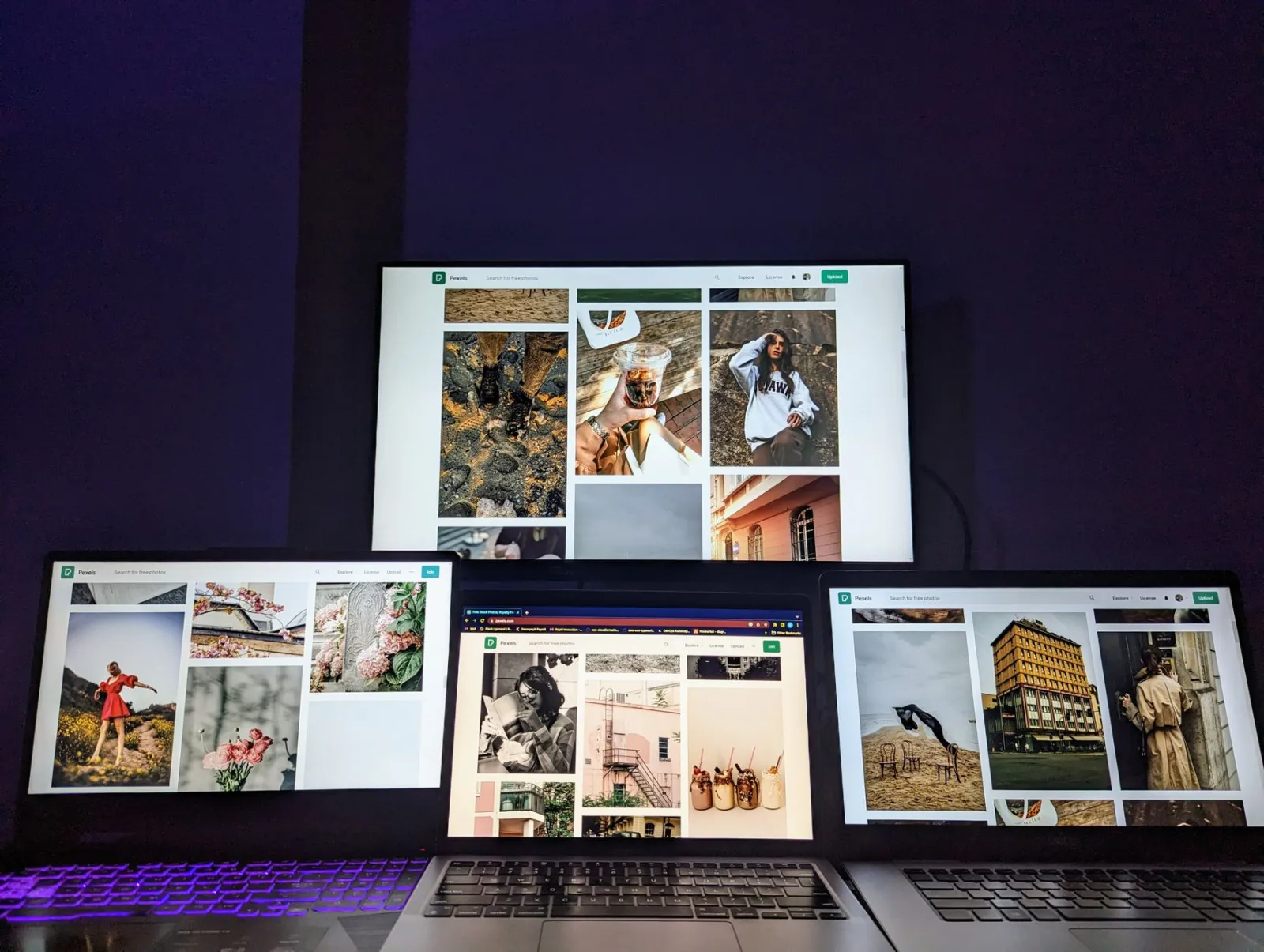 A high-tech workspace featuring three laptops and a monitor with various images displayed, highlighting technology and
