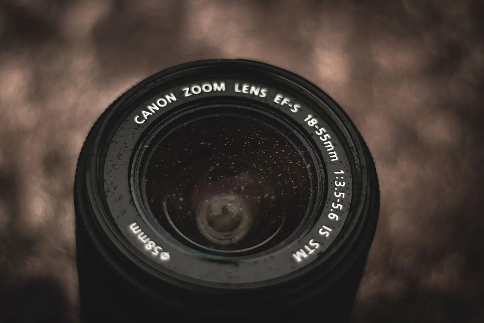 Close-up of a Canon zoom lens with water droplets, where optical resolution sets the detail ceiling