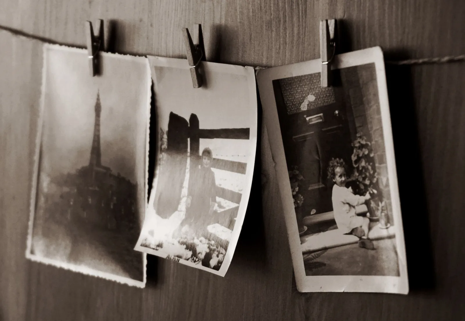 Grayscale vintage photographs clipped to a clothesline showing a faded sepia treatment