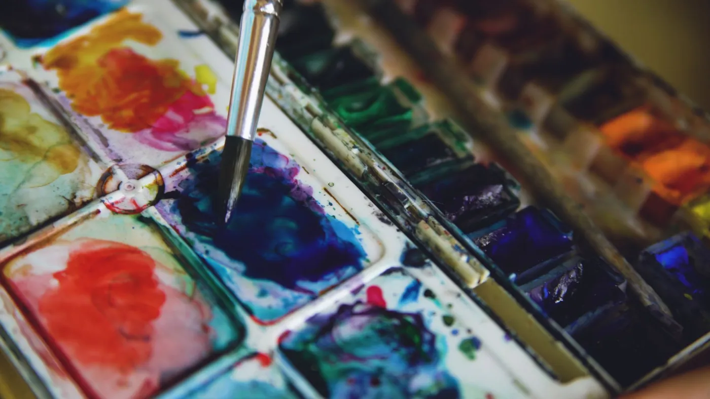 Close-up watercolor palette with a wet brush, showing pigment intensity and color mixing choices