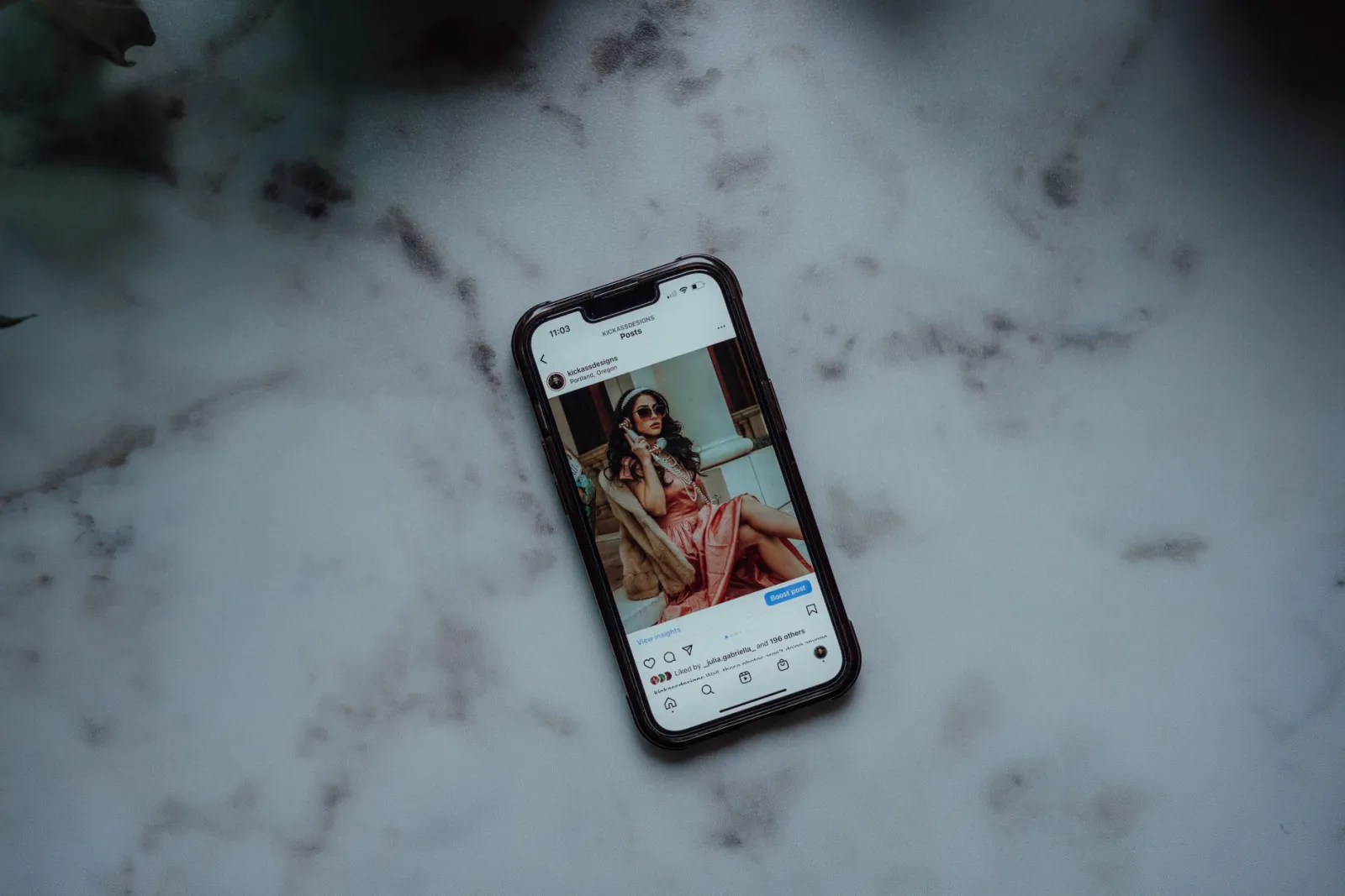 A smartphone showing an Instagram post against a marble background, showcasing modern social media use.