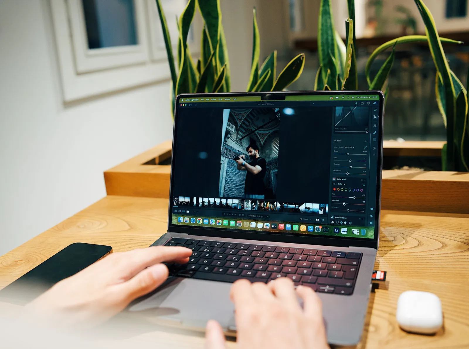 A photographer editing images in Lightroom on a laptop, the point where hidden image metadata is created and destroyed