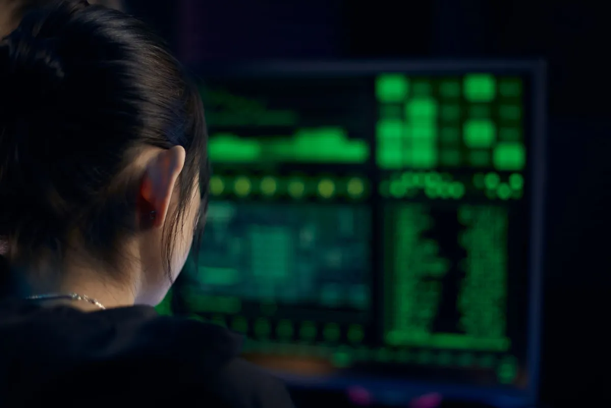 A person studying dense data on a monitor in a dark room, the kind of inspection needed to read image metadata