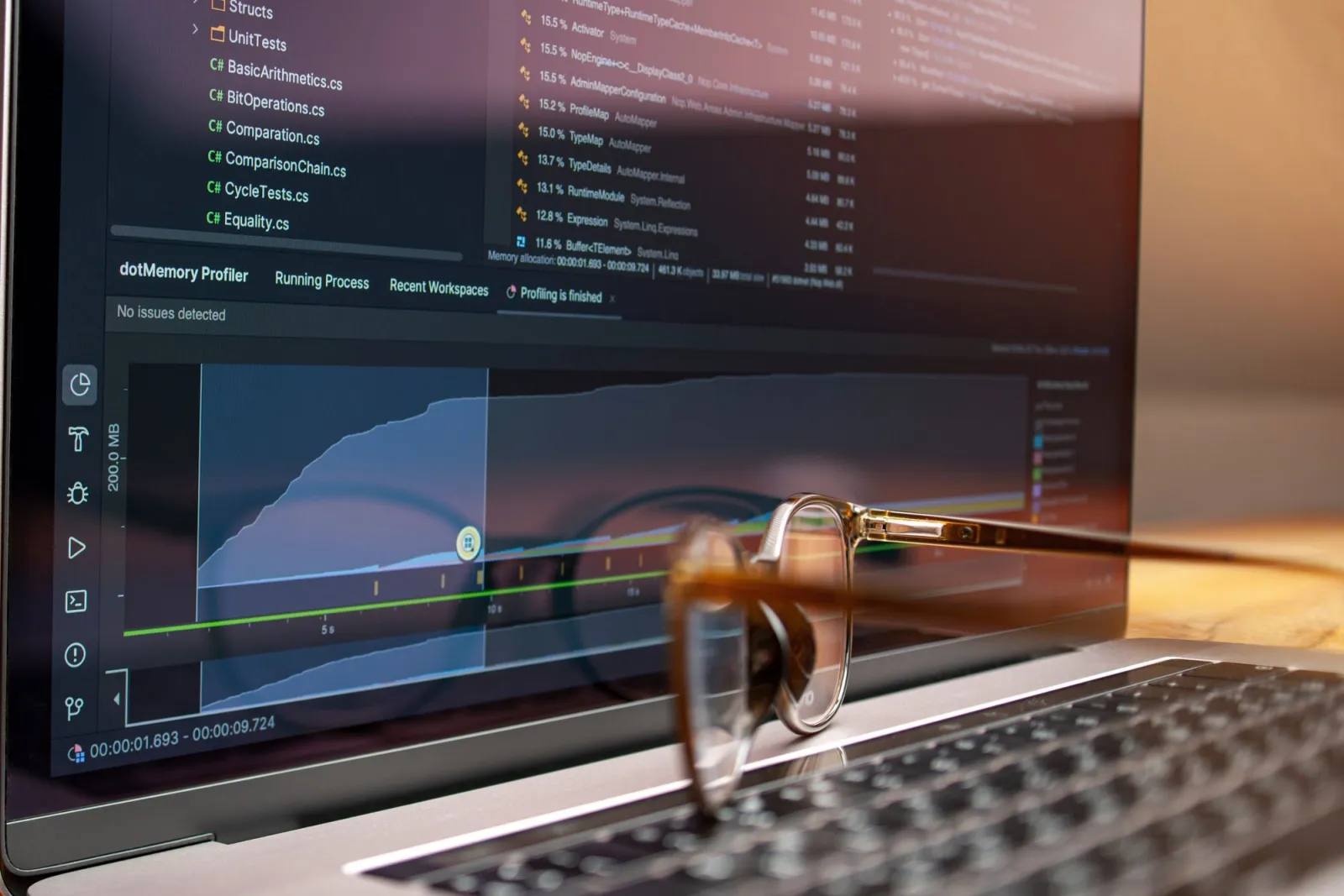 A laptop screen showing source code next to a performance metrics graph during a profiling session