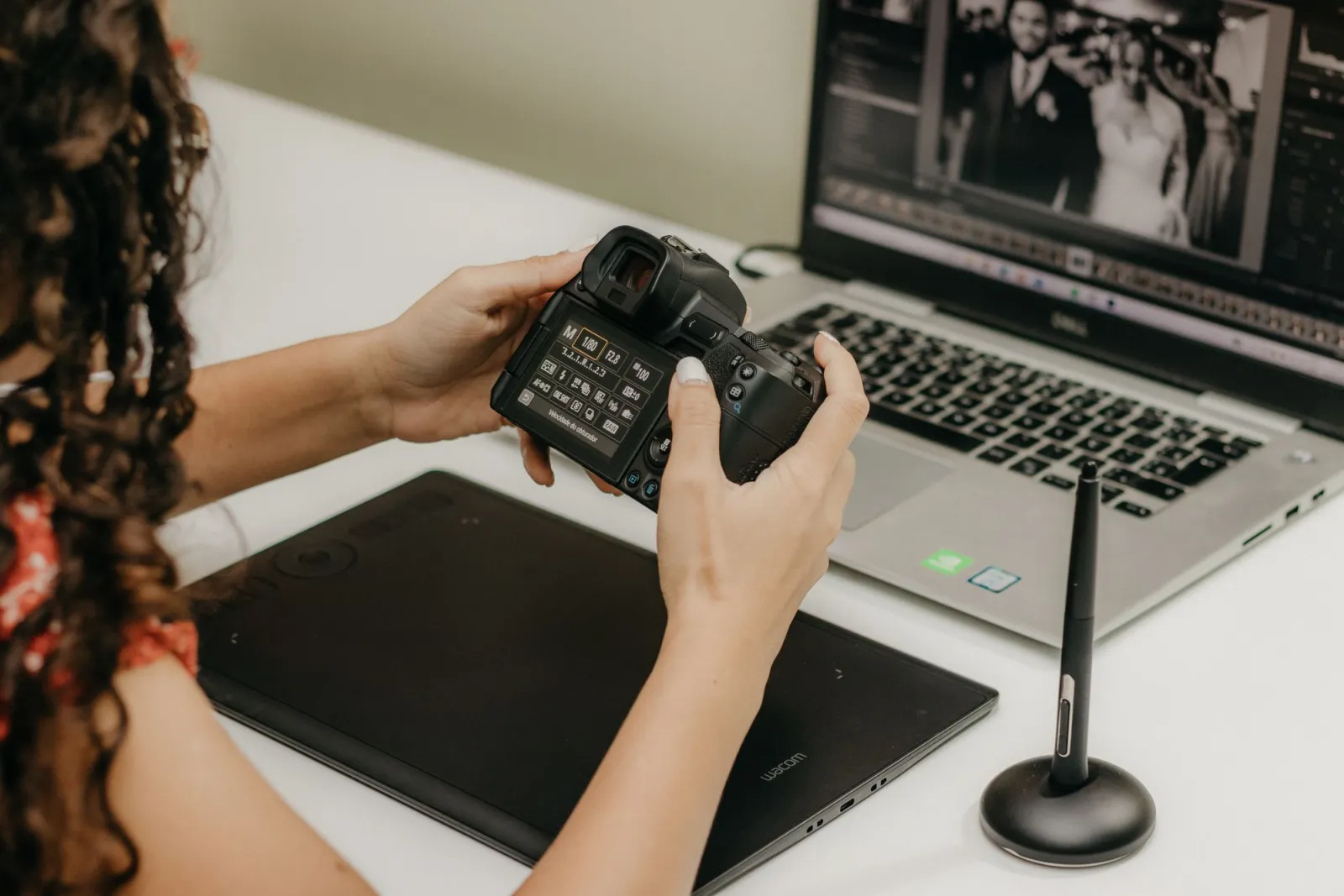 Hand using a stylus on a graphics tablet while editing photos in Adobe Lightroom
