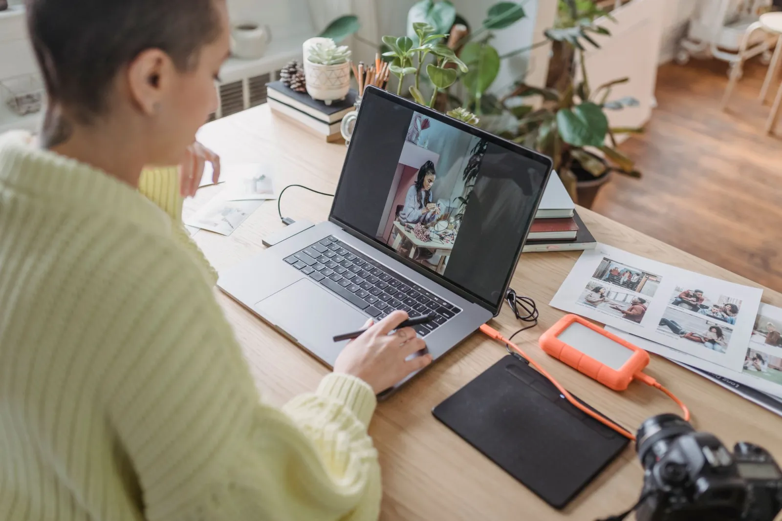Photographer editing photos on a laptop at a desk surrounded by camera gear