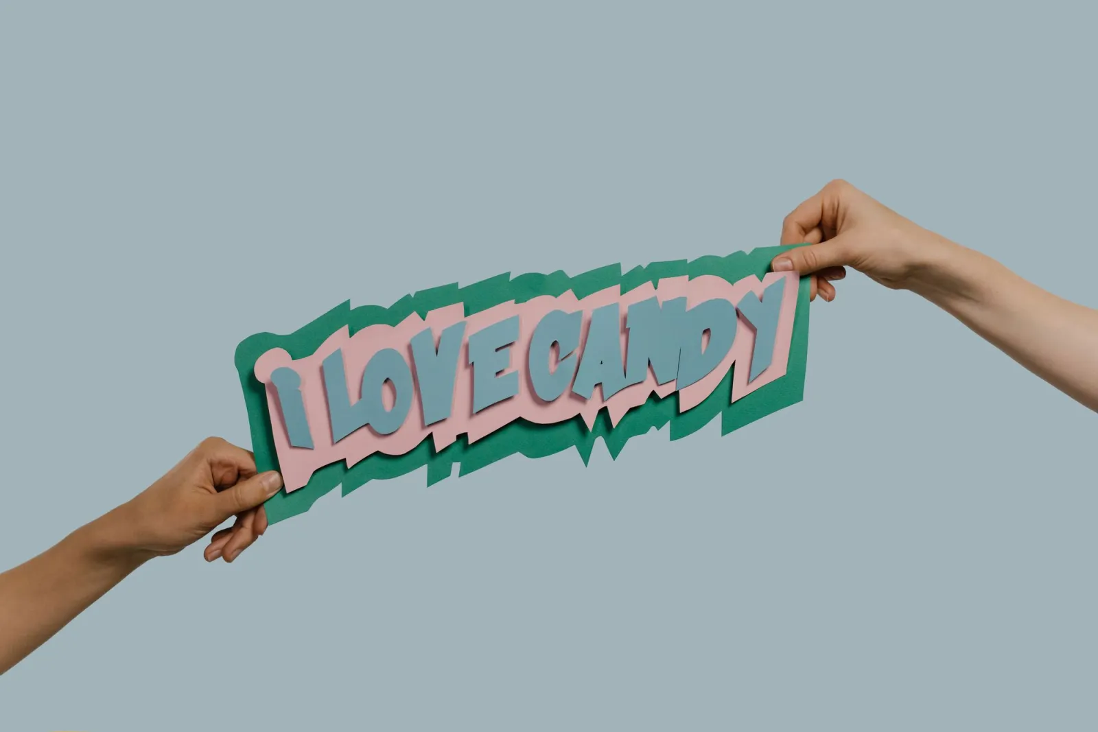 Hands holding a colorful paper cutout against a solid background