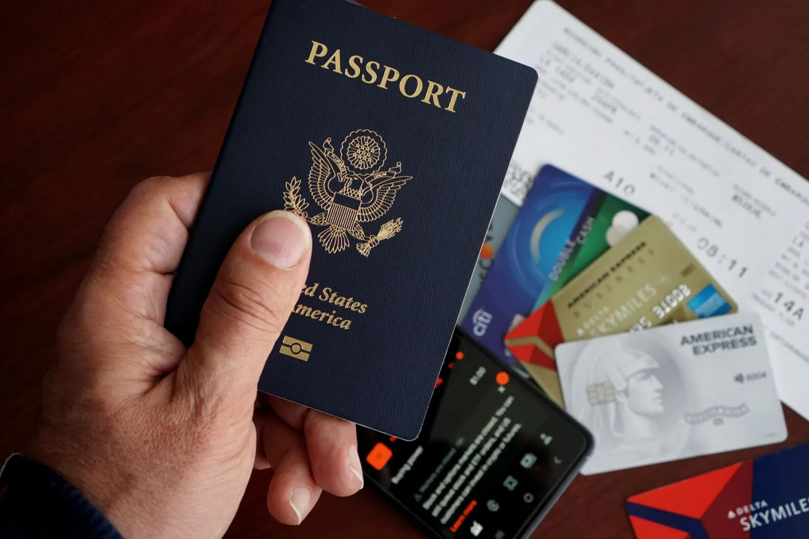 A US passport with credit cards, tickets, and a phone on a table
