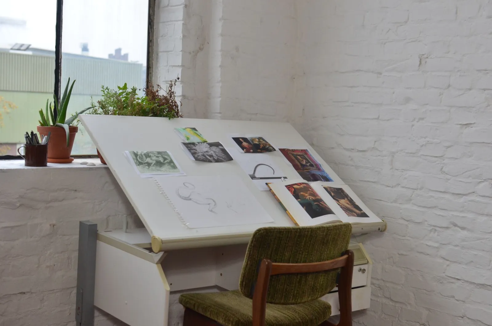 Interior of an art studio with drawings and sketches spread across a table