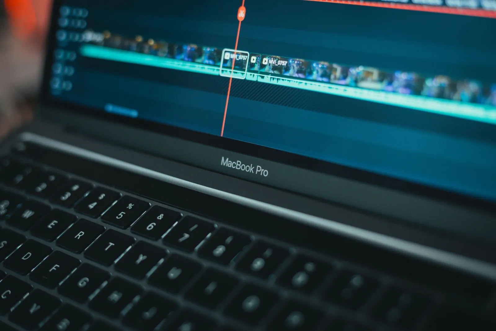 MacBook Pro running video editing software with the timeline visible on screen