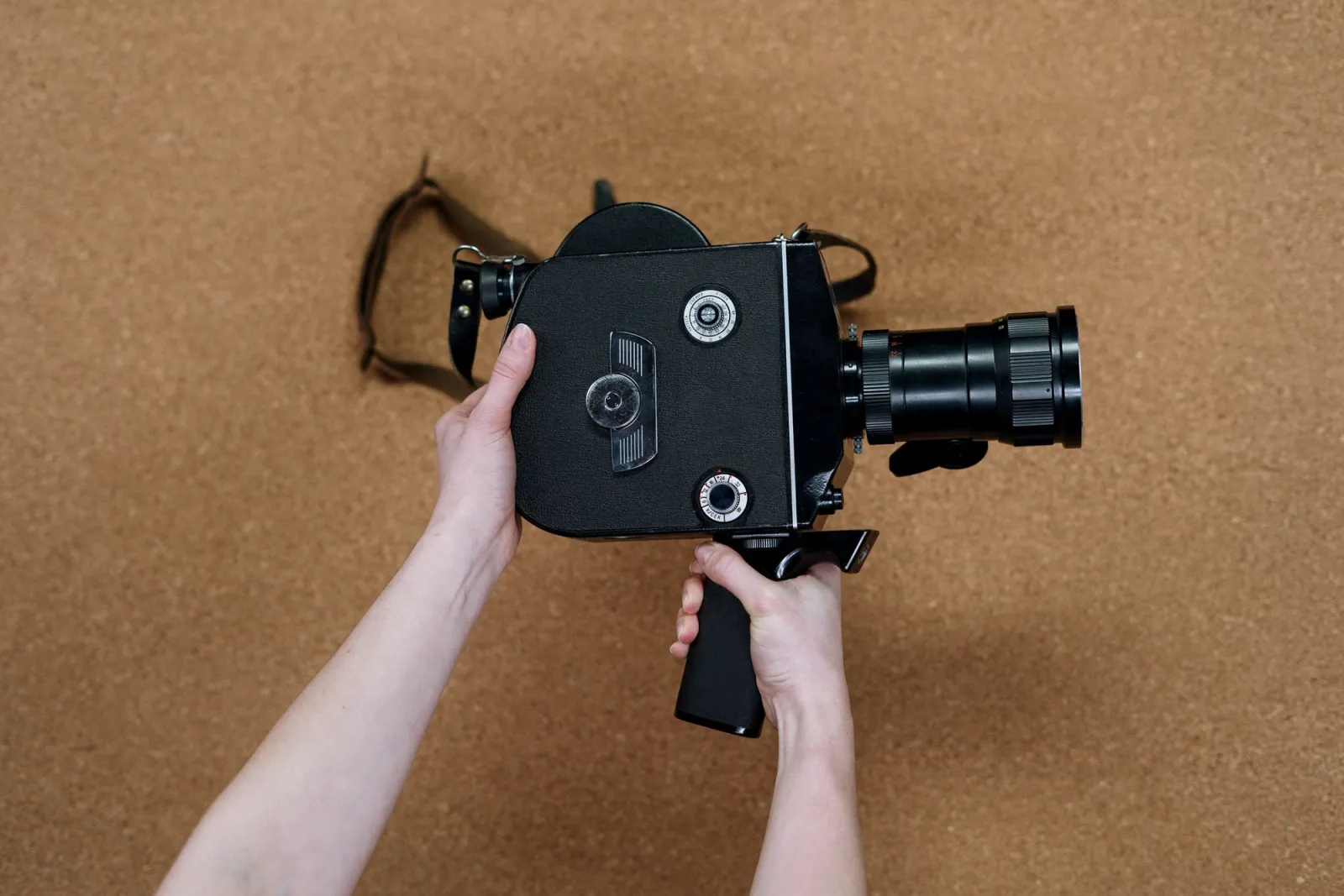 Filmmaker holding a vintage cinema camera over a corkboard background
