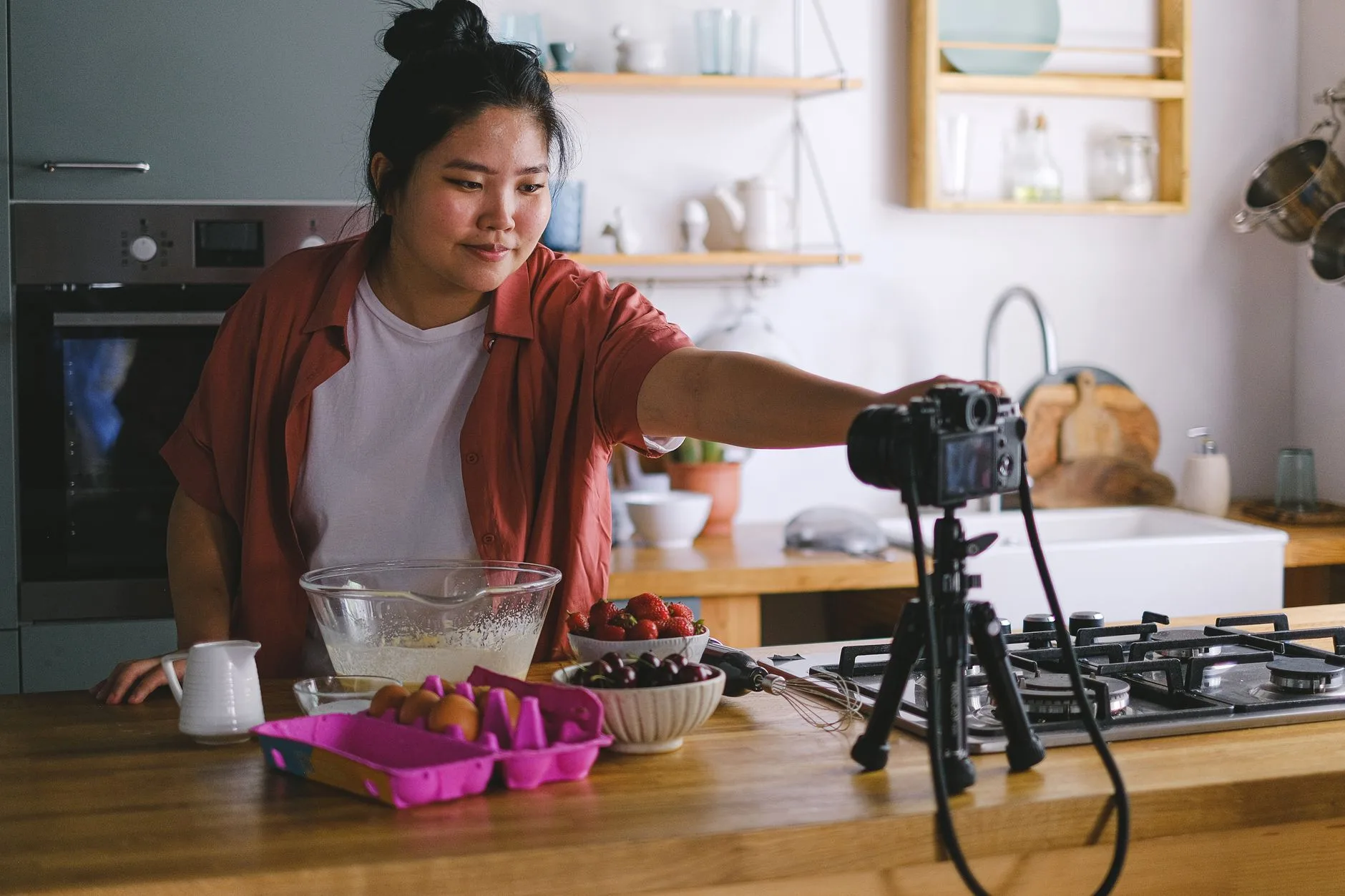 A woman filming a cooking vlog in a modern kitchen