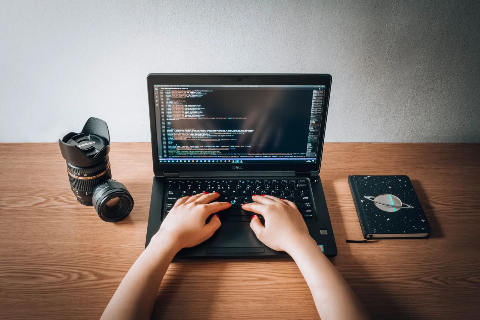 Close-up of colorful programming code on a screen with a laptop and notebook on a creative desk