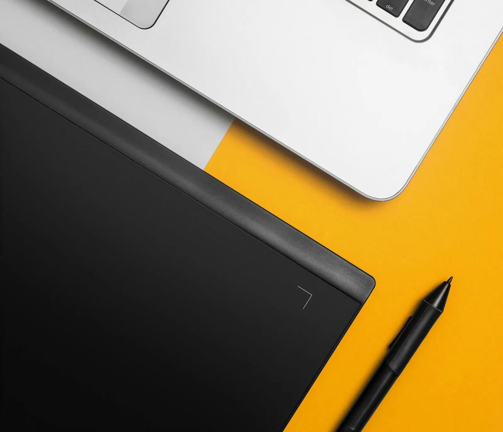 Overhead view of a laptop with a graphics tablet and stylus on a colorful designer desk