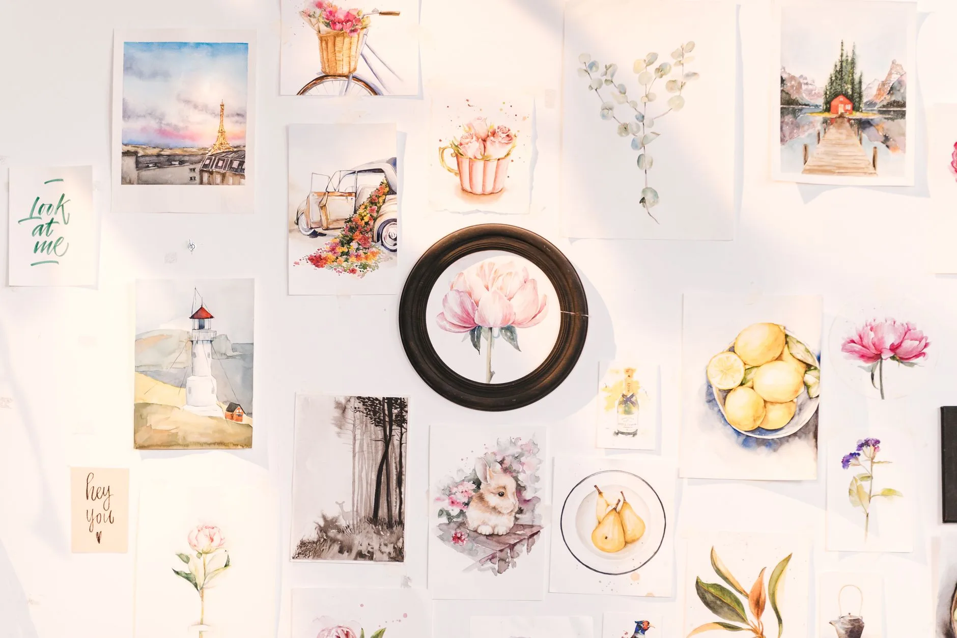 A collection of art prints of flowers, landscapes, and designs hanging on a wall