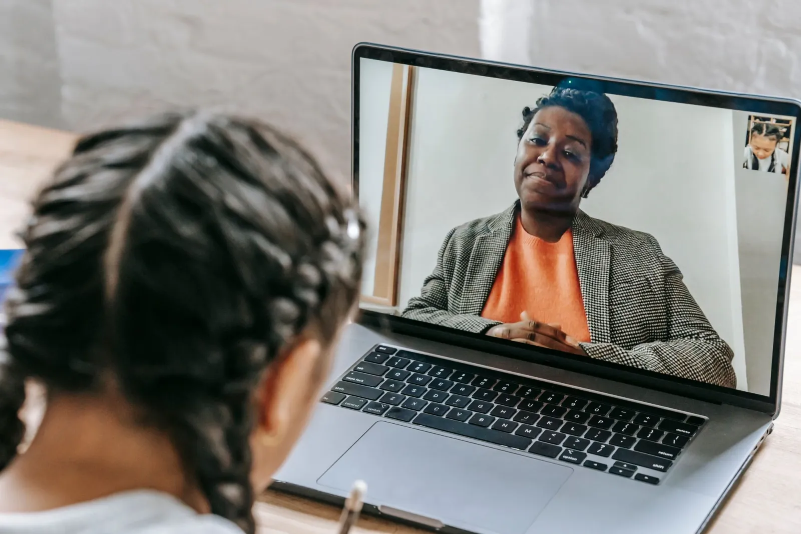 Student studying online with a tutor through a laptop screen at home