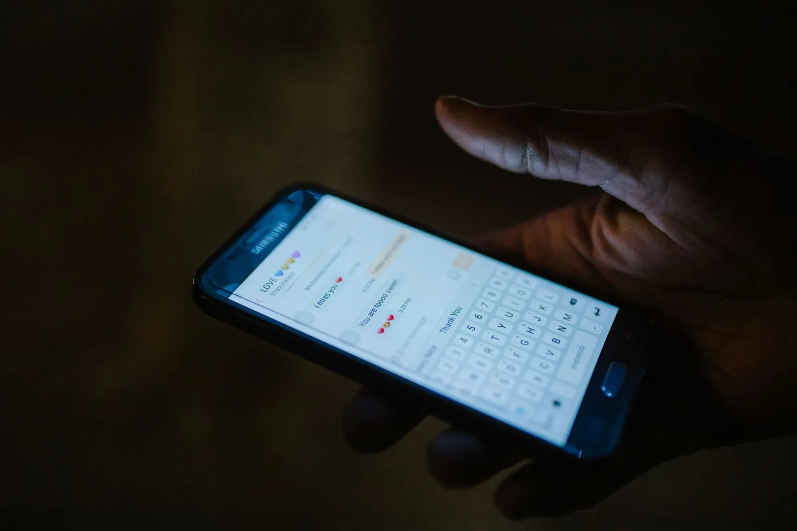 Hand holding a smartphone with a messaging app open