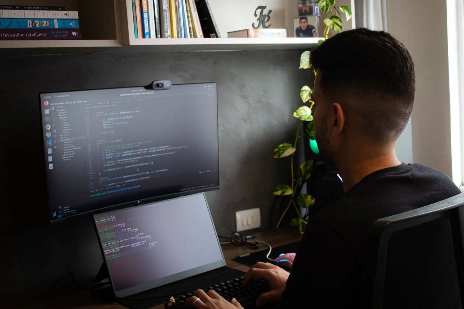 Programmer coding on a laptop and monitor in a modern office