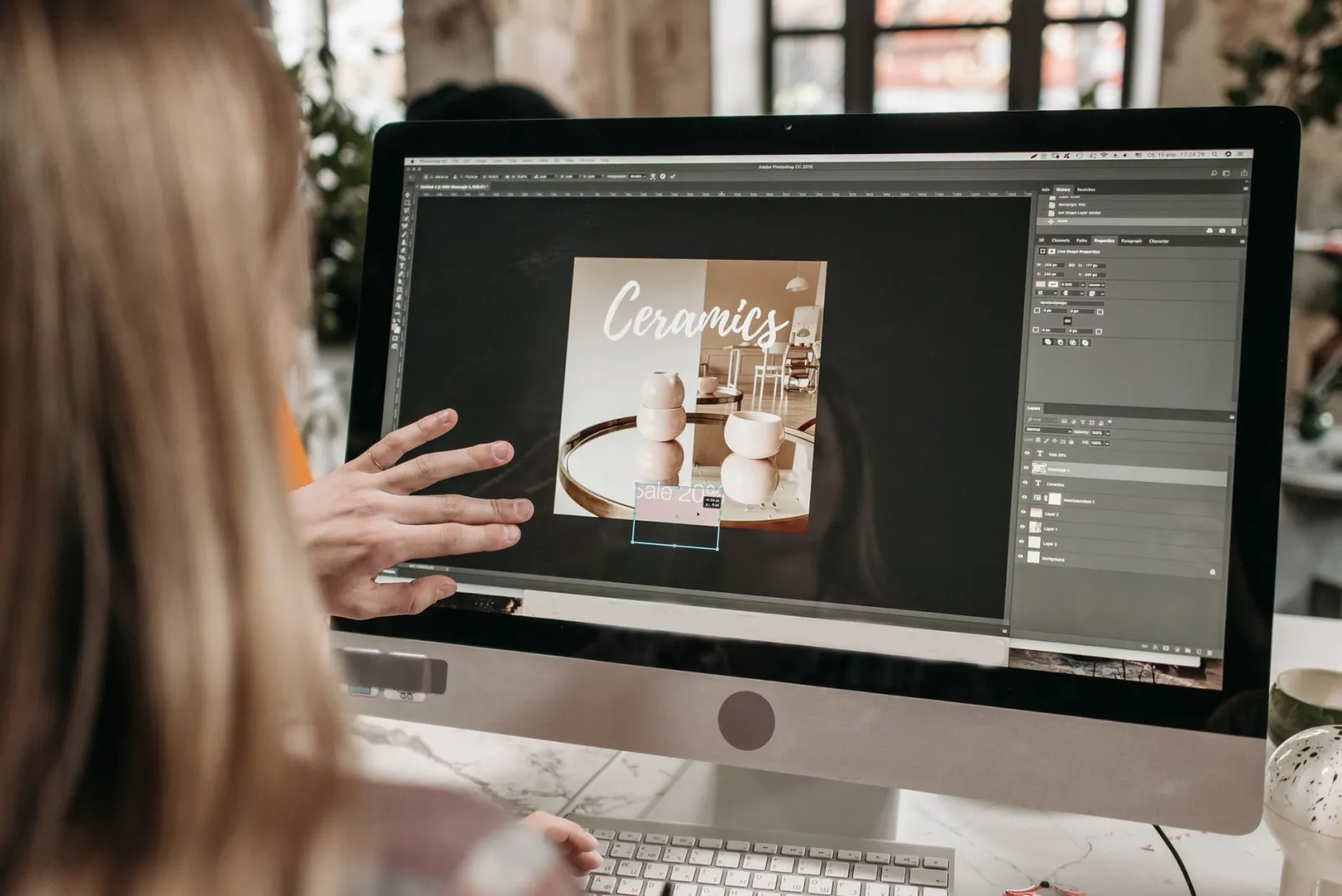 A designer working on a graphic in Photoshop on a desktop, the environment where thumbnails get their final text and contrast